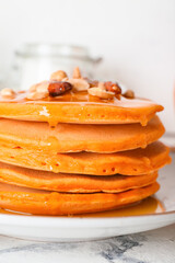 Tasty pumpkin pancakes with honey on plate, closeup