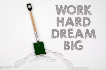 Work Hard Dream Big. Miniature shovel on a white paper