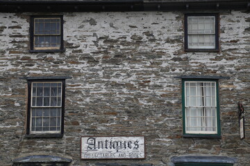 A very old, weathered Georgian building with original paned windows containing an Antiques and Collectables shop in Machynlleth, Wales, UK.