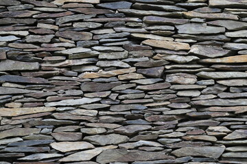 A closeup view of the slates in a dry stone slate wall in Wales.