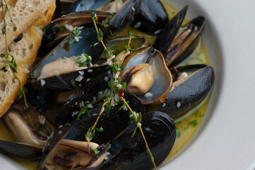 Mussels. Classic French or American restaurant appetizer: steamed mussels. Shellfish steamed with white wine, butter, garlic, onions and fresh herbs. Served with butter toasted baguettes.