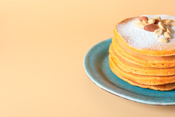 Plate with tasty pumpkin pancakes on color background