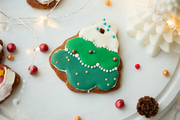 Tasty icing Christmas cookies on white table. Traditional Xmas gingerbread cookies