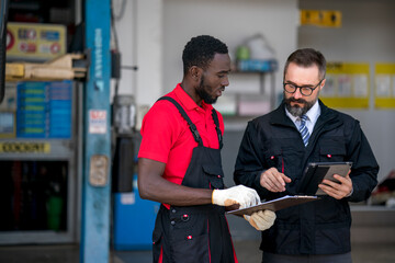 The mechanic discuss with his chief during car damage inspection at the garage 