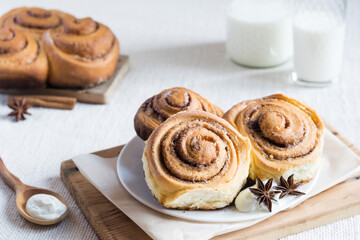 Cinnamon rolls. Homemade cinnamon buns on a plate on light rustic background, selective focus.