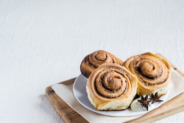 Cinnamon rolls. Homemade cinnamon buns on a plate on light rustic background, selective focus, copyspace.