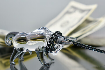 A glass figurine of a bull with a black metal chain around its neck stands against the background...