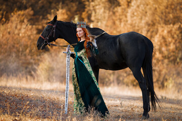 a Queen in a long green dress with a sword and crown and a horse