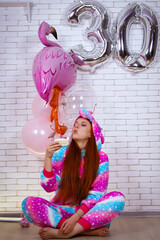 birthday girl in rainbow pajamas with balloons and cake 30 years old