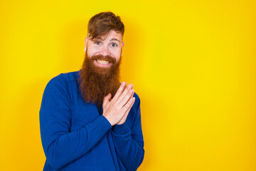 Young handsome red haired bearded man standing against yellow wall, feeling happy, smiling and clapping hands, saying congratulations with an applause.