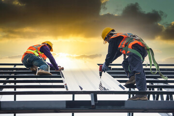Asian construction workers wear safety straps while working on the roof structure of the building...