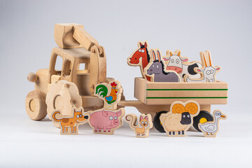Obraz premium wooden kids tractor toy with trailer and cartoon agricultural animals isolated on white background, close view 