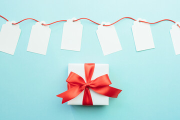 Blank gift tags mock-ups with red ribbon and gift box with bow on blue background. Discount or sale concept.  