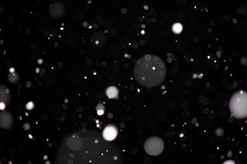 Freeze motion of white powder coming down, isolated on black, dark background. Abstract design of falling dust cloud. Particles cloud screen saver, wallpaper with copy space. Rain, snow fall concept