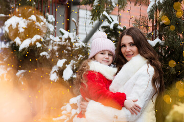 Mom and Child girl on the walk in snowy city decorated for Christmas day. girl  play outdoors in winter. 