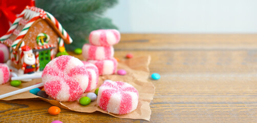 Christmas composition with gingerbread house, peppermint candies and sweets over holiday background. Festive banner with copyspace.