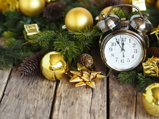 Fototapeta na wymiar Retro alarm clock on the eve of Christmas among the fir branches and Christmas balls of gold color. Everything in yellow style. Greeting card for Christmas and New Year