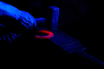 Blacksmith forges a hot horseshoe close up.