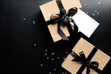 Christmas gifts and blank paper card mockup on black background with confetti. Xmas presents.