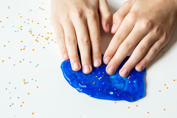 Children's hands make a blue slime on a white background. Close-up.