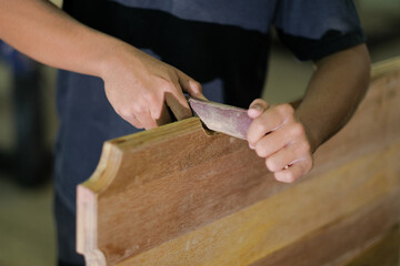 Young carpenter in work clothes and face mask  using sand paper in finishing work  for console table