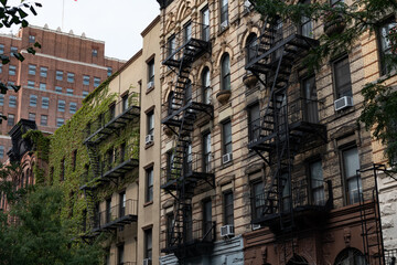Row of Old Brick Residential Buildings with Fire Escapes and Green Ivy in Chelsea New York