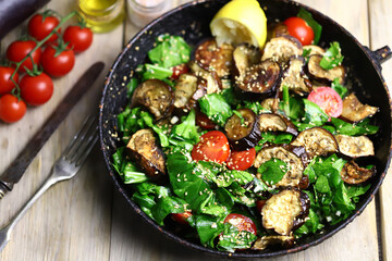 Selective focus. Warm salad with spinach and eggplant in a frying pan. Healthly food. Vegan lunch idea.