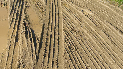 Muddy road with tyre tracks different tread patterns. Muddy wet track near a farm