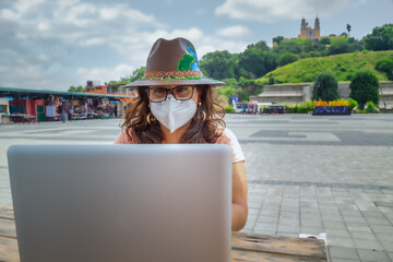 Closeup of a girl with a protective mask working on a laptop - new normal