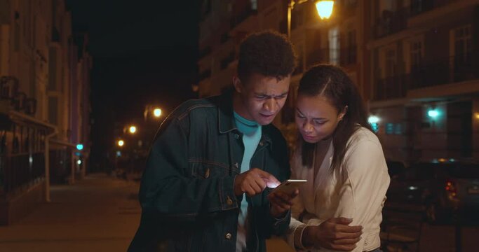 Young couple of tourists getting lost in city, looking for way, online maps app