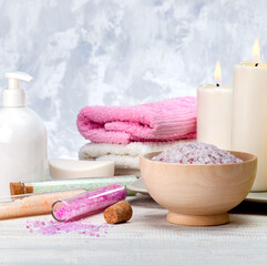 Spa, beauty treatment and wellness background with sea salt, towels, cosmetic products and burning candles.