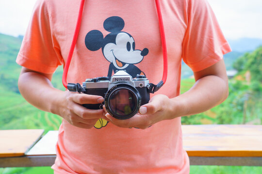 SAPA/VIETNAM - - JULY 15: Nikon FE and 50 mm f1.2 Lens Cute old film camera Made in japan. on 07 15 2019 Men wearing Orange t-shirts Mickey Mouse.