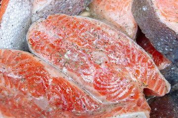 Fresh trout steaks are marinated in a metal bowl before cooking