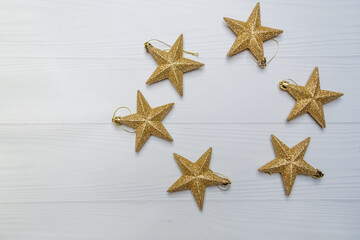 Fototapeta na wymiar Christmas toys golden stars on a light background laid out in a circle with copy space