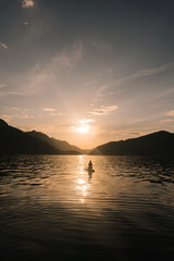 Girl at sunset on the lake on a stand-up paddle board in Altai