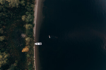 Aerial view from a drone to a boat on the lake and a girl on a stand-up paddle over a sunken ship...