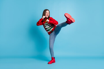 Full length body size photo of funny female student pretending to fight karate keeping one leg up shouting loudly wearing xmas outlook isolated on blue color background © deagreez