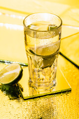 sliced lime in glass with alcohol cocktail on yellow