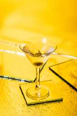 green olive in glass of martini on yellow