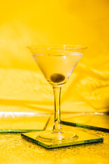 green olive in glass with martini on yellow