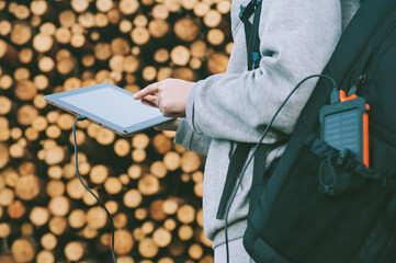 Powerbank in a backpack pocket. Against the background of a girl with a finger near the screen of the tablet in his hands and logging.
