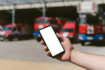 Mock up of a smartphone in the hand of a man. Against the background of fire trucks.