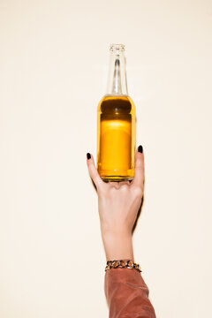 Cropped View Of Woman Showing Rock Sign While Holding Bottle With Beer On White