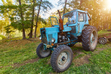 An old blue tractor stands in a farmyard