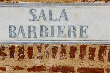 old sign barber /sign made of cement indicating the writing barber on a bricks wall