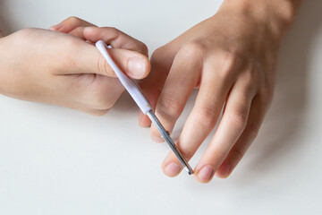 
Child cuts his fingernails with scissors on a white background. Close-up.