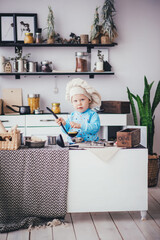 Kid boy in chef's hat and ladle in the kitchen