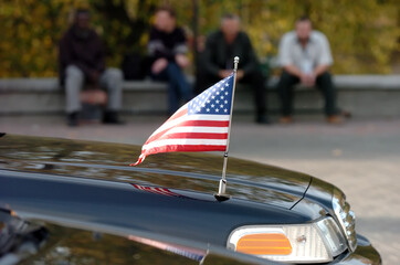 Closeup of American flag attached to car. people in the background