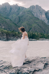 Fototapeta na wymiar Bride in a wedding dress against the background of the river and mountains in Altai