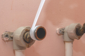 Installing a water tap in the bathroom. Winding fum tape on the sleeve of the pipe for sealing....